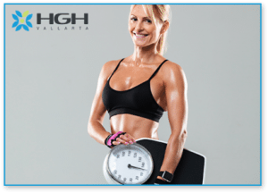 Female body builder holding a scale with both hands to represent weight loss and show muscle gain.